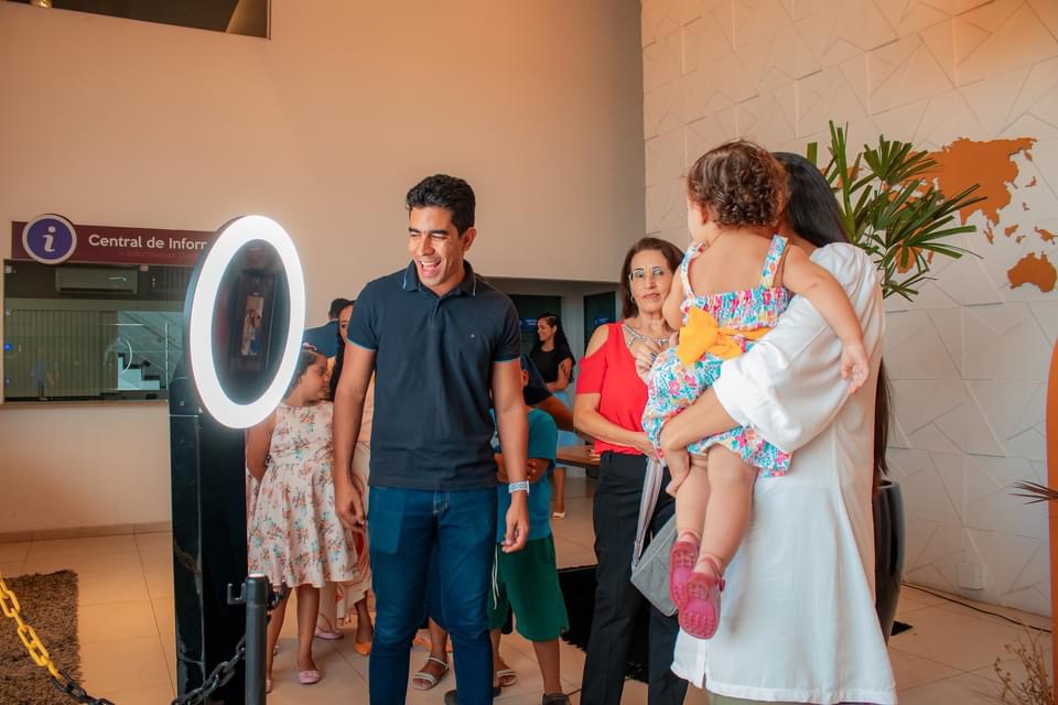 Família com crianças interagindo com o totem fotográfico em evento público
